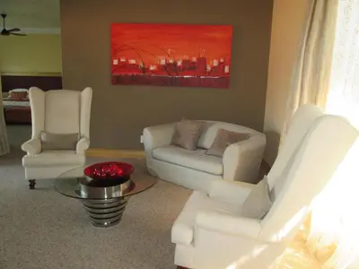 a living room with two white chairs and a table at Schneiders Boutique Hotel in White River