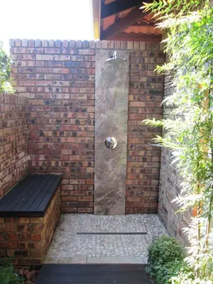 a shower in a brick wall with a bench at Schneiders Boutique Hotel in White River