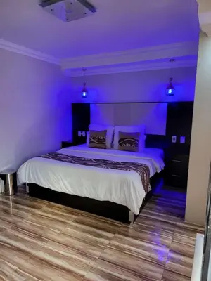a bedroom with a bed with purple lights on it at Zurich garden lodge benoni in Benoni