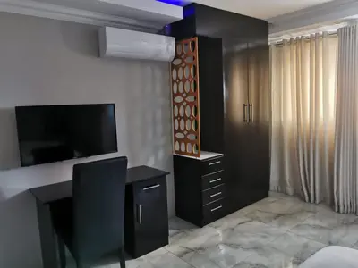 a room with a desk and a tv and a bedroom at Zurich garden lodge benoni in Benoni