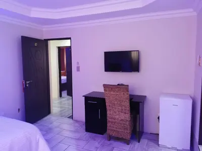 a bedroom with a bed and a desk and a television at Zurich garden lodge benoni in Benoni