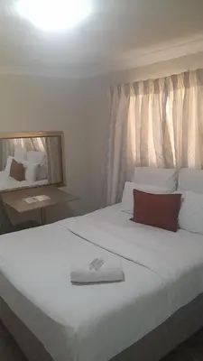 a bedroom with a large white bed and a mirror at Zurich garden lodge benoni in Benoni