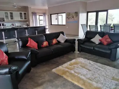 a living room with black leather furniture and red pillows at Hazyview Bogarts Villa in Hazyview