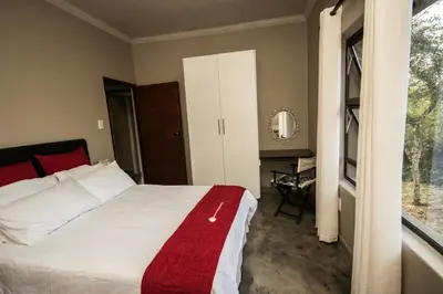 a bedroom with a bed with a red blanket on it at Hazyview Bogarts Villa in Hazyview