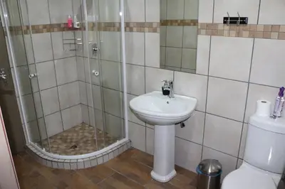 a bathroom with a shower and a sink and a toilet at Hummingbird's Nest in Nelspruit