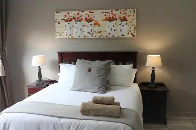 a bedroom with a white bed with two lamps at Hummingbird's Nest in Nelspruit