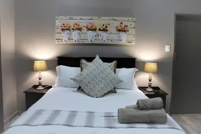 a bedroom with a white bed with two lamps at Hummingbird's Nest in Nelspruit