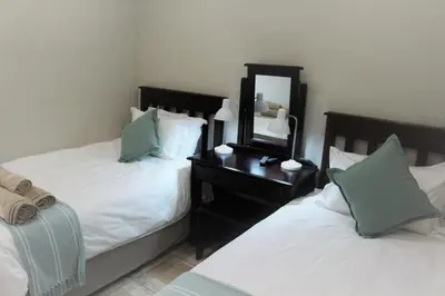 a bedroom with two beds and a mirror on a night stand at Hummingbird's Nest in Nelspruit
