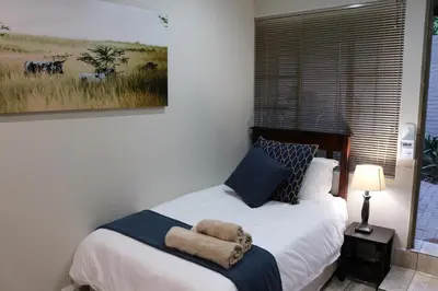 a bedroom with a bed with a painting on the wall at Hummingbird's Nest in Nelspruit