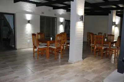 a dining room with wooden chairs and a table at Hummingbird's Nest in Nelspruit