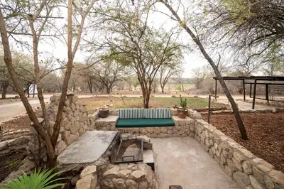 a stone wall with a bench and a table at Foxy Crocodile Bush Lodge & Kruger Safaris in Marloth Park