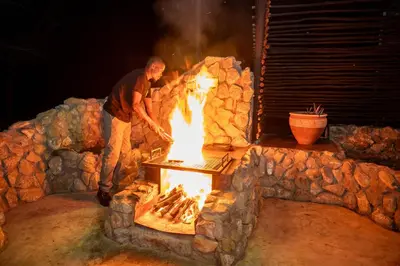 a man standing next to a fire oven at Foxy Crocodile Bush Lodge & Kruger Safaris in Marloth Park