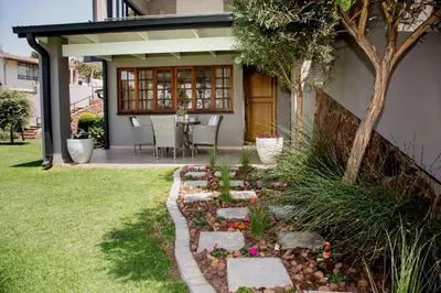 a patio with a table and chairs in a yard at La Vida Luka - Luxury Guesthouse in Pretoria