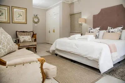 a large bedroom with two beds and a chair at La Vida Luka - Luxury Guesthouse in Pretoria