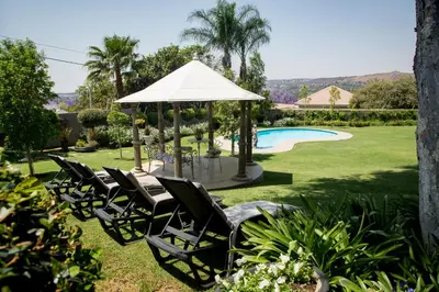 a group of chairs and a gazebo next to a pool at La Vida Luka - Luxury Guesthouse in Pretoria