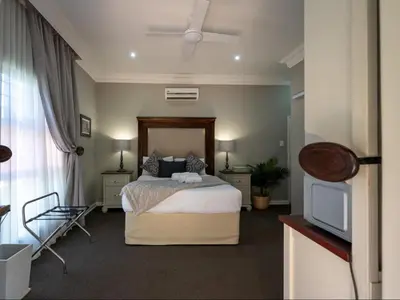 a bedroom with a bed and a flat screen tv at Familia Guesthouse & Boutique Hotel in Groblersdal