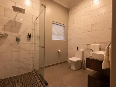 a bathroom with a shower and a toilet and a sink at Familia Guesthouse & Boutique Hotel in Groblersdal