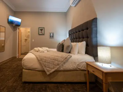 a bedroom with a large bed with a large headboard at Familia Guesthouse & Boutique Hotel in Groblersdal
