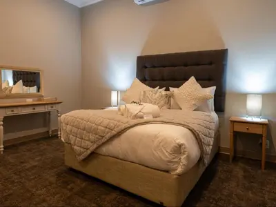 a bedroom with a large bed and a mirror at Familia Guesthouse & Boutique Hotel in Groblersdal