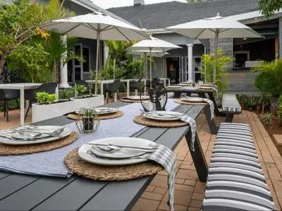 a patio with tables and chairs and umbrellas at Familia Guesthouse & Boutique Hotel in Groblersdal