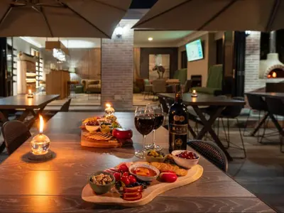 a table with a plate of food and a glass of wine at Familia Guesthouse & Boutique Hotel in Groblersdal