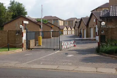 a gate on a street with a row of houses at Eric's Apartments in Centurion