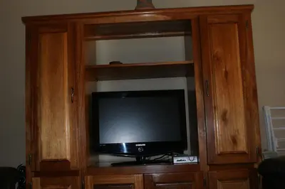 a television in a wooden entertainment center at Eric's Apartments in Centurion