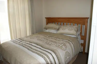 a bedroom with a bed with a wooden headboard and pillows at Eric's Apartments in Centurion