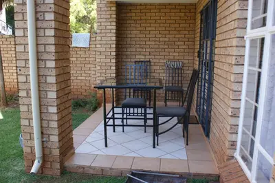 a patio with a table and chairs in a brick wall at Eric's Apartments in Centurion