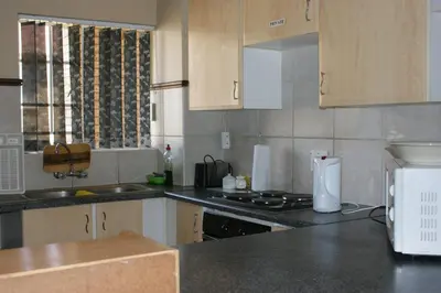 a kitchen with black counter tops and wooden cabinets at Eric's Apartments in Centurion