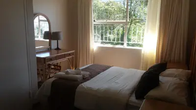a bedroom with a bed and a desk and a window at Magoebaskloof Mountain Lodge in Magoebaskloof