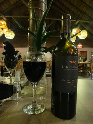 a bottle of wine sitting next to a glass of red wine at Magoebaskloof Mountain Lodge in Magoebaskloof