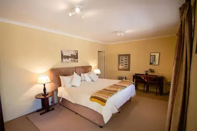 a bedroom with a large bed and a desk at Auldstone House in Dullstroom