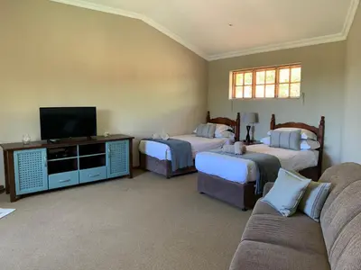 a living room with two beds and a flat screen tv at Auldstone House in Dullstroom