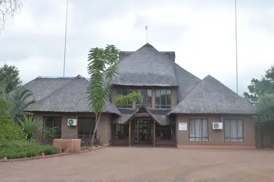 a house with a thatched roof and a palm tree at Copacopa Lodge and Conference Centre in Punda Maria