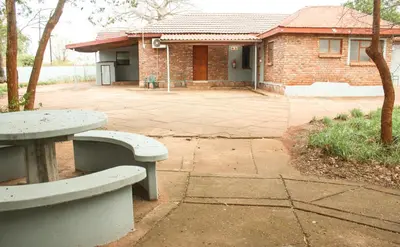a brick house with two benches in front of it at Copacopa Lodge and Conference Centre in Punda Maria