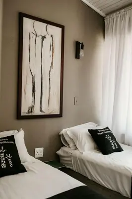 a bedroom with two beds and a painting on the wall at Overnight Stop Before Kruger National Park in Phalaborwa