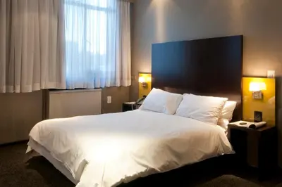 a bedroom with a large white bed with a blue headboard at Manhattan Hotel in Pretoria