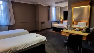 a hotel room with two beds and a mirror at Manhattan Hotel in Pretoria