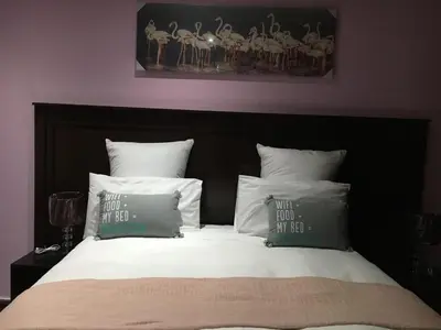 a bed with a black head board with pillows and a painting at Tassili Lodge in Kempton Park