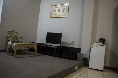 a living room with a small refrigerator and a table at Tassili Lodge in Kempton Park