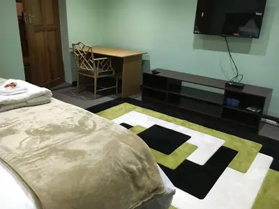 a bedroom with a bed and a desk and a television at Tassili Lodge in Kempton Park