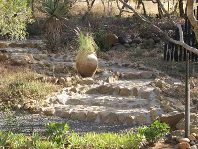 a stone path in a garden with a vase on it at Ukuthula Hideaway in Kampersrus AH