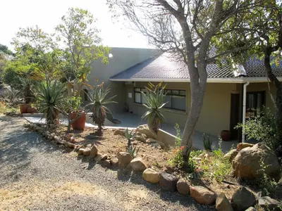 a house with trees and rocks in front of it at Ukuthula Hideaway in Kampersrus AH