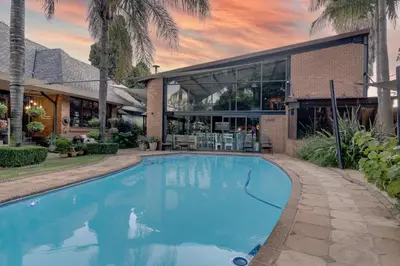 a large blue swimming pool in front of a building at Sunrock Guesthouse in Kempton Park