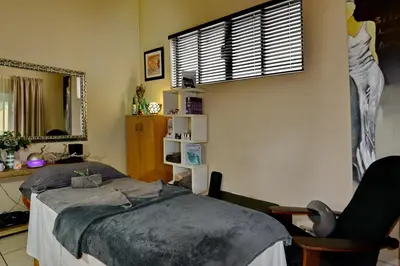 a bedroom with a bed and a chair and a window at Sunrock Guesthouse in Kempton Park