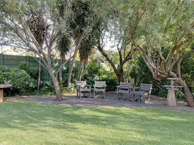 a park with chairs and a fountain and trees at Sunrock Guesthouse in Kempton Park