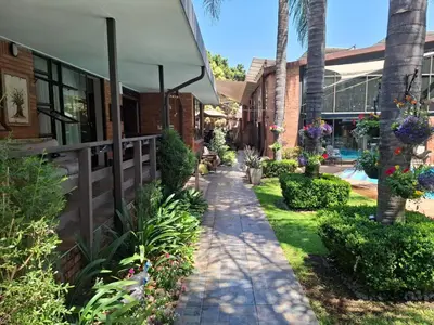 a walkway in front of a building with flowers at Sunrock Guesthouse in Kempton Park