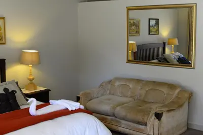 a living room with a couch and a mirror at Avant Garde Lodge in Kempton Park