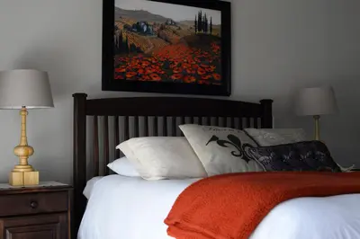 a bedroom with a bed with a painting on the wall at Avant Garde Lodge in Kempton Park